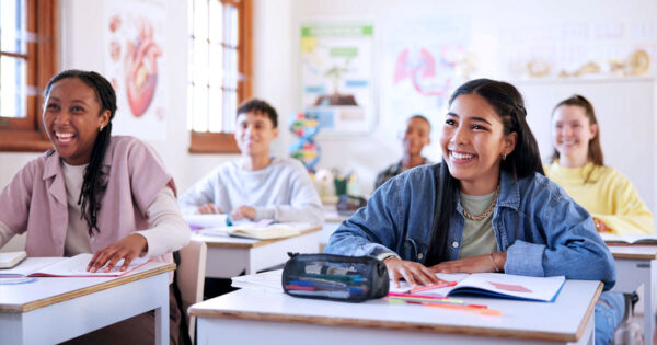 Happy students in a classroom facing the front of the class