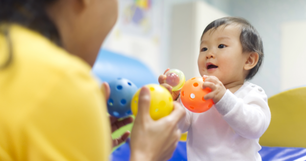 A caregiver and a baby playing with and counting plastic balls.